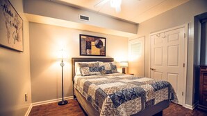 A bedroom with a bed, a floor lamp, a wall art piece, and a door. - Water St. Retreats 03 Historic riverfront paradise (Wilmington)