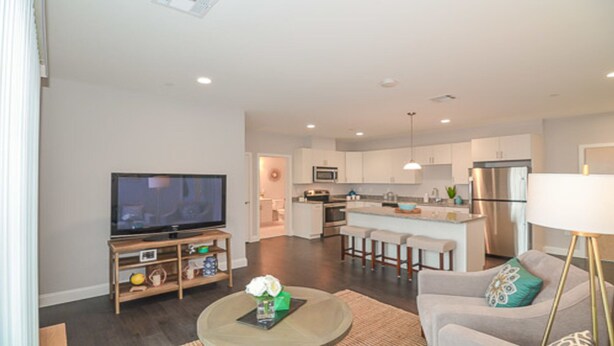 A modern living room with a flat-screen TV, a coffee table, and a sofa.