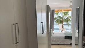 Ein Flur mit Blick auf einen Balkon, auf dem sich ein Bett und eine Palme befinden.