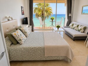 Une chambre d’hôtel avec un lit, un canapé, une petite table et une vue sur l’océan.