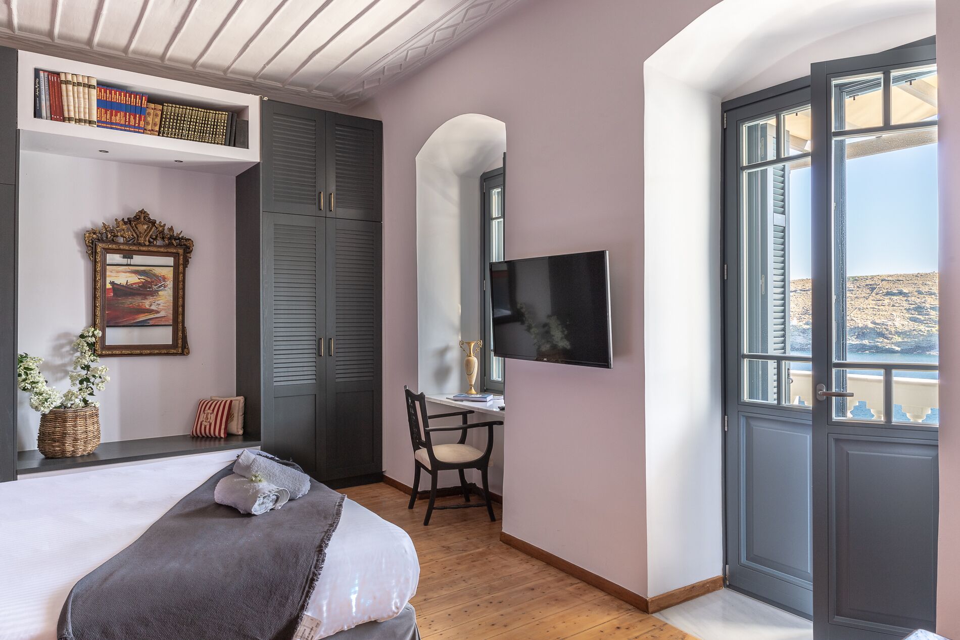 Una camera da letto con un letto, una scrivania con una sedia, una televisione, una libreria e una finestra vista.
