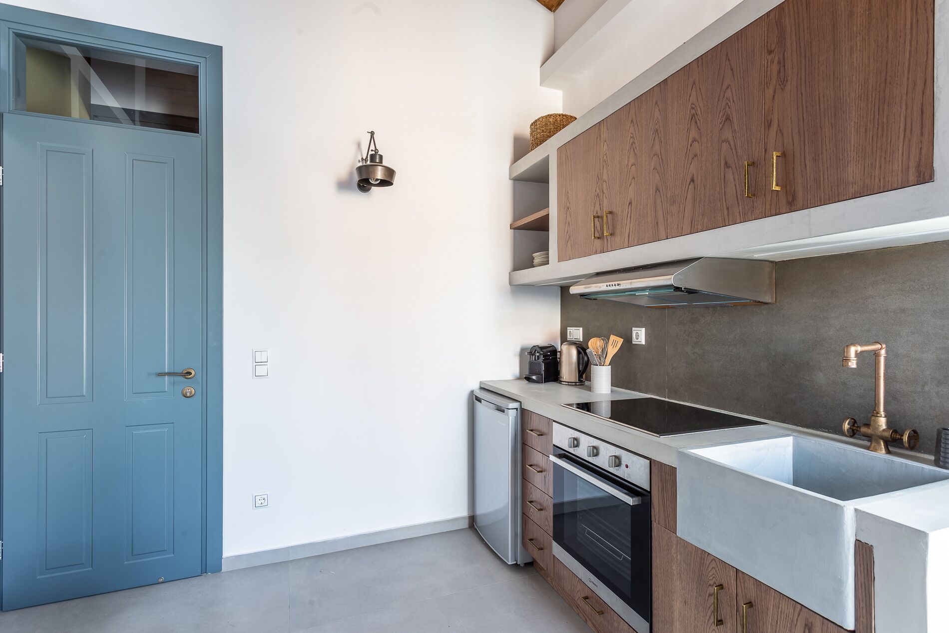 Eine moderne Küche mit blauer Tür, Edelstahlgeräten, Holzschränken und einem eingebauten Backofen.