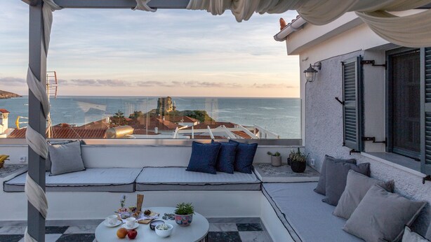 A balcony with a view of the sea and a building with a white facade.