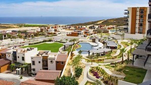 Un resort con piscina, aree verdi e vista sull'oceano.