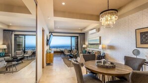 Una camera d'albergo moderna con zona pranzo, un lampadario e un'ampia finestra con vista sul mare.
