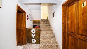 Un couloir étroit avec un bureau en bois portant l’inscription « OYO », un escalier et des portes en bois.