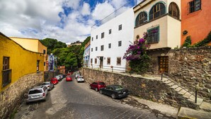 Une rue étroite, bordée de voitures garées et d’immeubles des deux côtés.