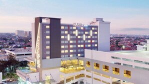Ein mehrstöckiges Harris Hotel mit modernem Design, das durch einen markanten vertikalen Streifen an der Fassade und einen Poolbereich auf dem Dach gekennzeichnet ist.