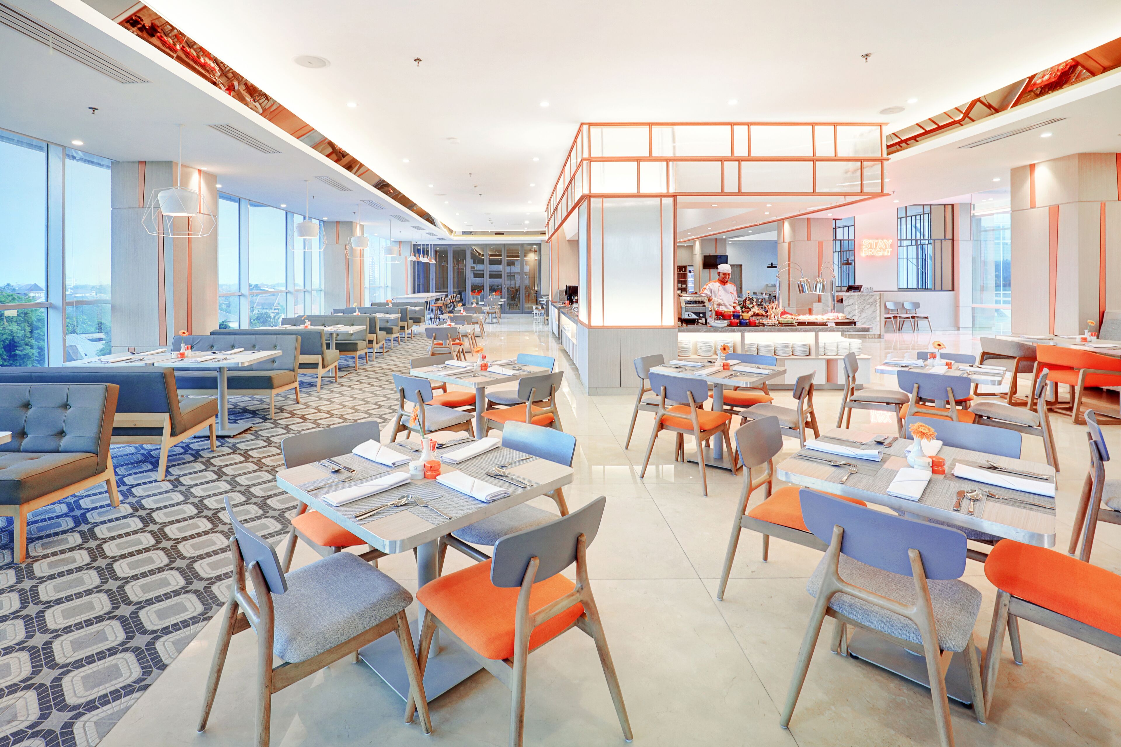 Un restaurant moderne doté de hauts plafonds, de grandes fenêtres et d’un espace cuisine central.