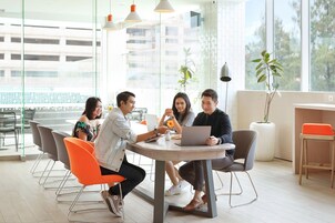 Une salle de réunion moderne dotée d’une table ronde, de sièges confortables et de grandes fenêtres offrant une vue sur la ville.