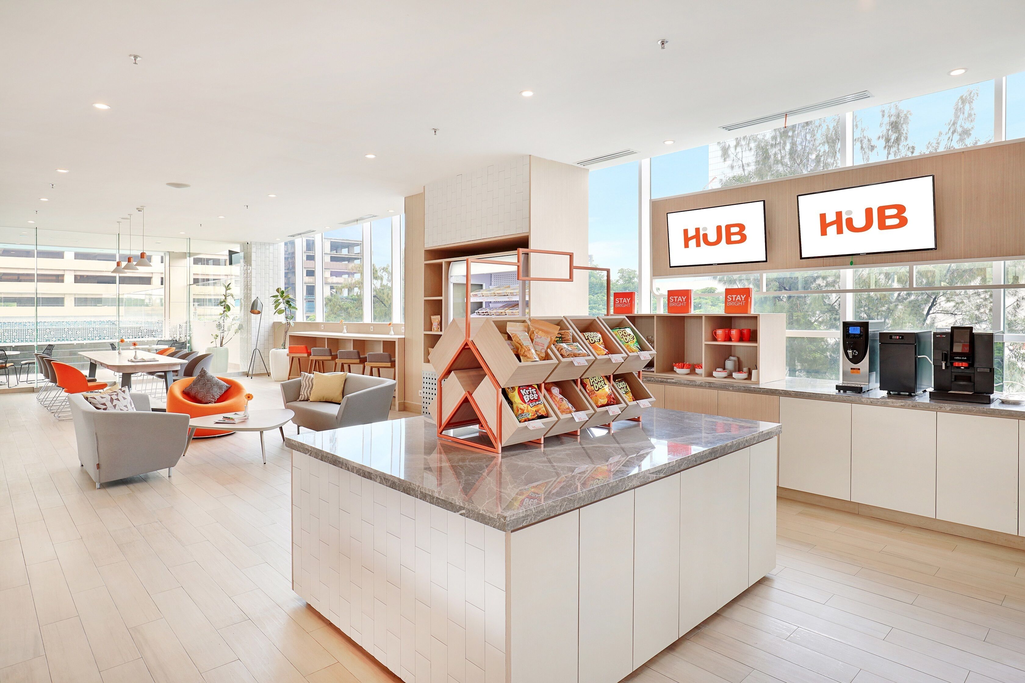 A modern hotel lobby with a central island, seating area, and a coffee station.
