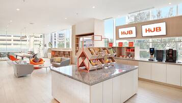 A modern hotel lobby with a central island, seating area, and a coffee station.