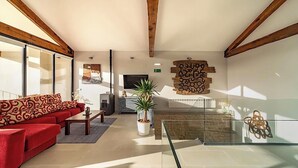 A spacious living room with a red sofa, a glass coffee table, and a fireplace.
