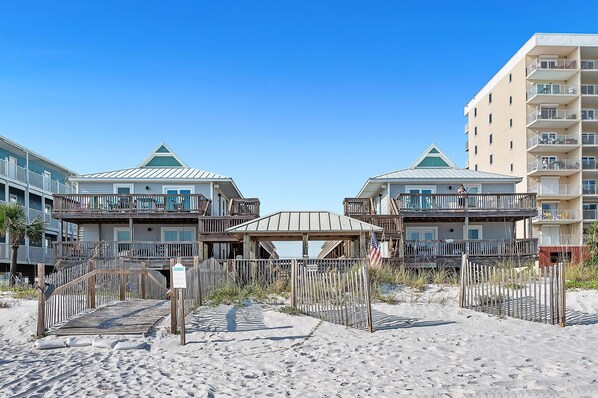 A beachfront hotel with multiple balconies, a covered walkway, and a sandy beach area.