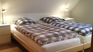 Un dormitorio con dos camas, suelo de madera y lámparas de noche.
