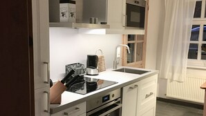 Una cocina moderna con armarios blancos, horno empotrado y microondas.