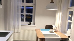 Una cocina compacta con una mesa de comedor, sillas y una lámpara colgante.