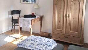 Una sala de estar acogedora con un aparador de madera, una mesa con una silla y un cuadro en la pared.