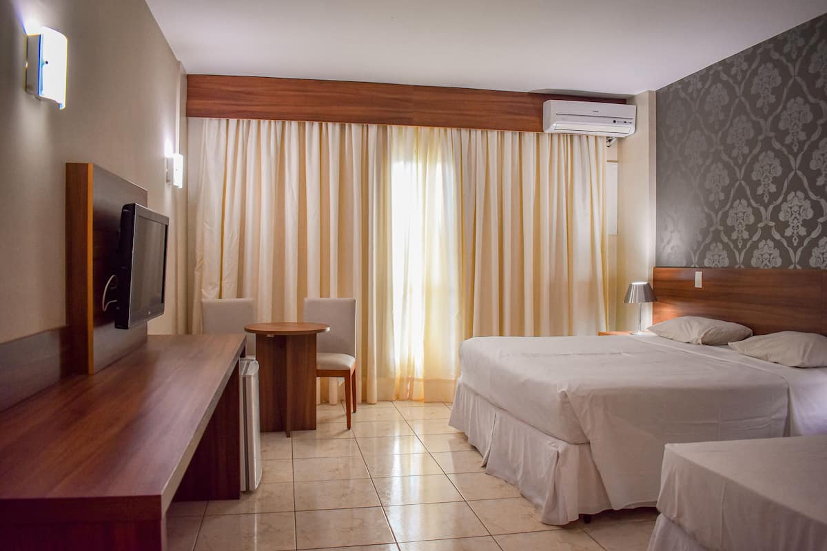 A hotel room with a bed, a desk, a chair, and a television.