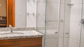 Un baño con ducha acristalada, tocador de madera y espejo.