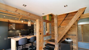 A modern kitchen with a wooden staircase, bar seating, and pendant lighting.
