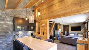 A modern kitchen with a wooden island, stone walls, and a built-in stove.