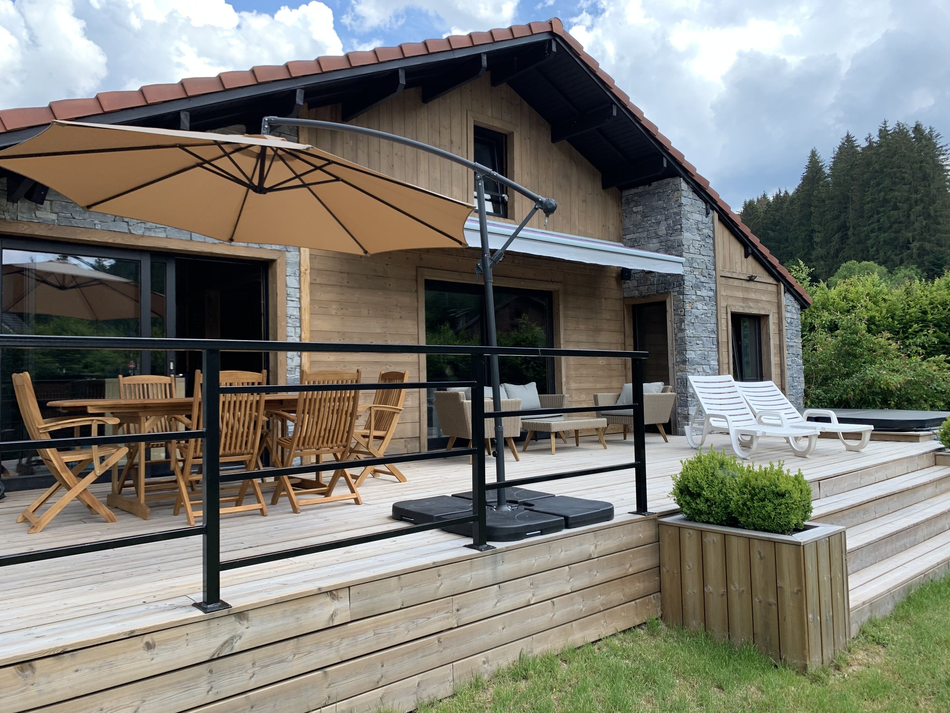 A wooden cabin with a deck, outdoor seating, and a hot tub.
