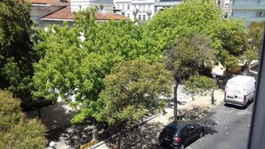 Vista de la calle con árboles, un coche aparcado y una camioneta blanca.