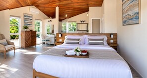 A spacious bedroom with a large bed, wooden headboard, and a wooden ceiling.