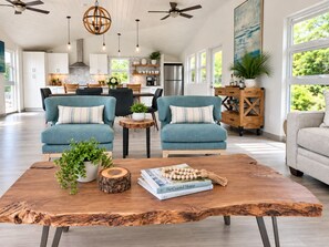 A spacious living area with a large wooden coffee table, two blue armchairs, and a sofa.