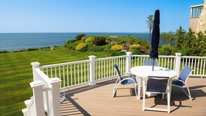 Eine Terrasse mit weißem Zaun, einem Tisch mit Stühlen und einem Sonnenschirm.