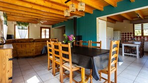 Een gezellig eetgedeelte met een houten tafel en stoelen, een plafondventilator en uitzicht op de keuken.