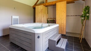 Een moderne badkamer met een houten jacuzzi, een douchegedeelte en een betegelde vloer.