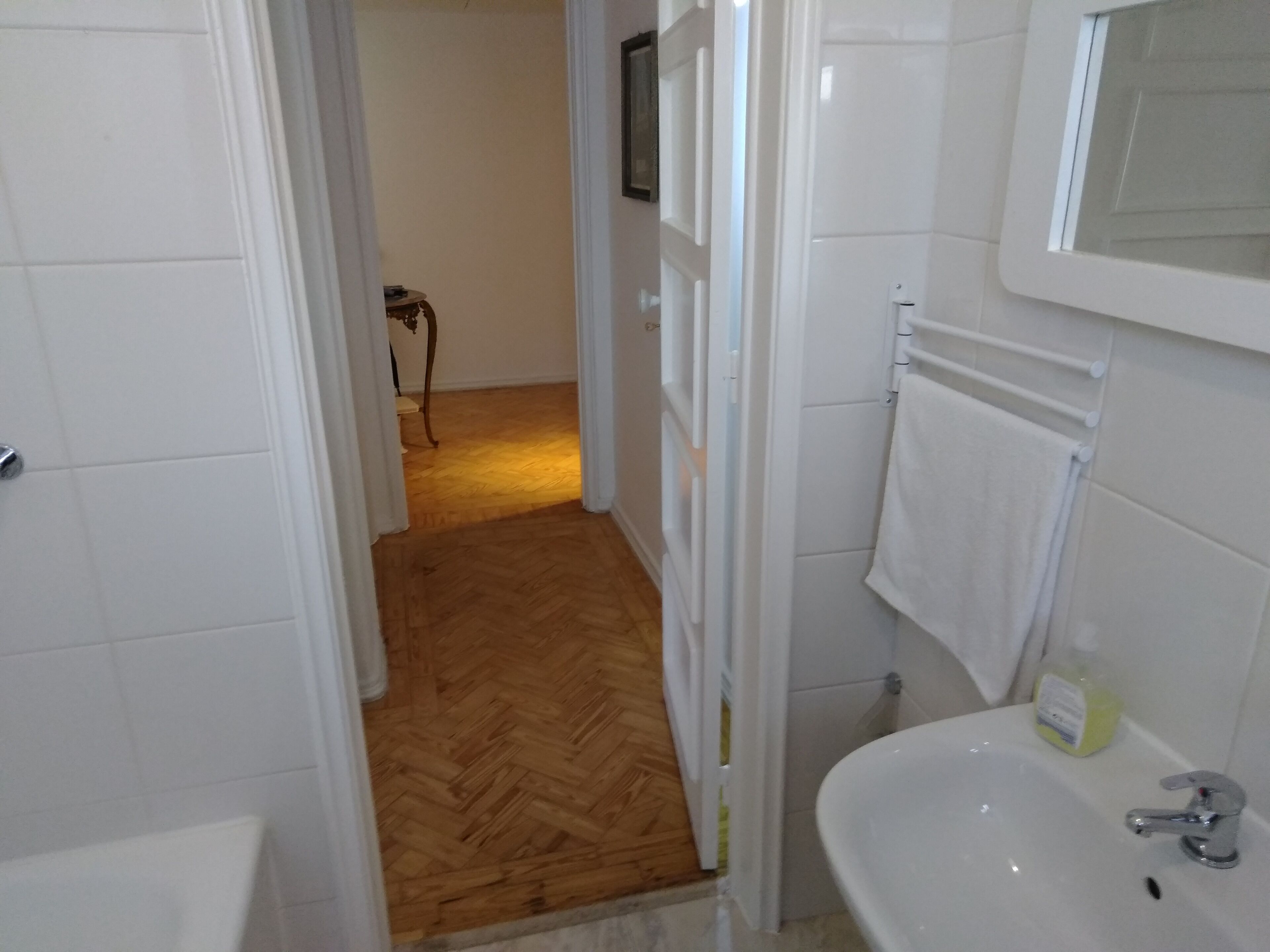 A bathroom with a white sink, a mirror, and a wooden floor.
