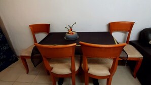 Un coin repas avec une table et quatre chaises, une petite plante décorative posée sur la table et un canapé adossé au mur.