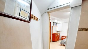 Une salle de bain avec un lavabo blanc, un miroir et une porte donnant sur une autre pièce.