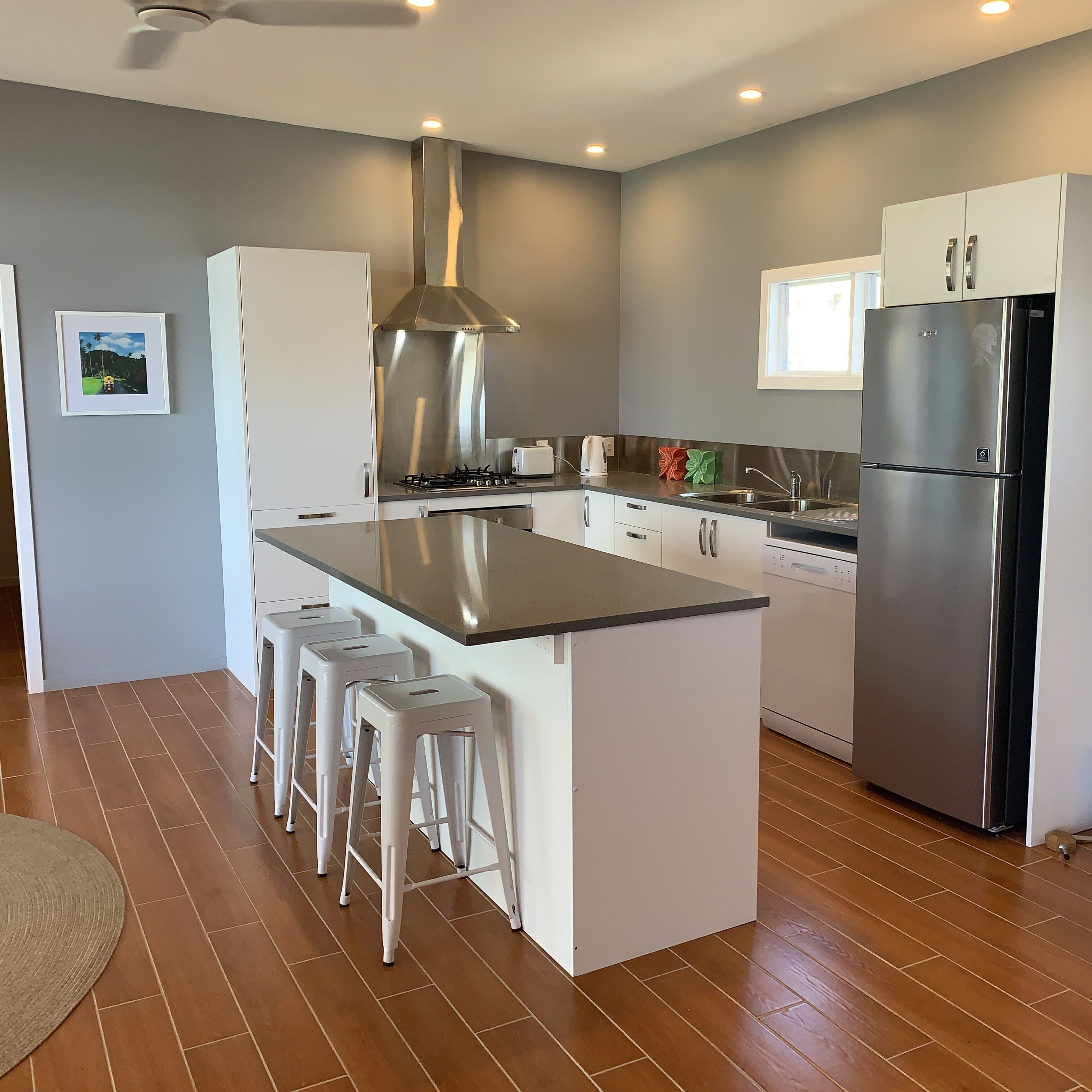 Una cocina moderna con una isla central, electrodomésticos de acero inoxidable y muebles de cocina blancos.