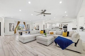 A spacious living room with a sectional sofa, a coffee table, and a ceiling fan. - Luxury Scottsdale Home:6BR W/8 Beds, 4BA,Heated Pool, HotTub,Putting Green,&More (Scottsdale)