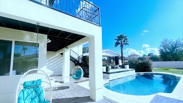 A modern two-story house with a swimming pool, outdoor seating, and a clear blue sky. - Luxury Scottsdale Home:6BR W/8 Beds, 4BA,Heated Pool, HotTub,Putting Green,&More (Scottsdale)
