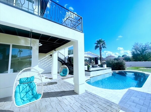 A modern two-story house with a swimming pool, outdoor seating, and a clear blue sky. - Luxury Scottsdale Home:6BR W/8 Beds, 4BA,Heated Pool, HotTub,Putting Green,&More (Scottsdale)