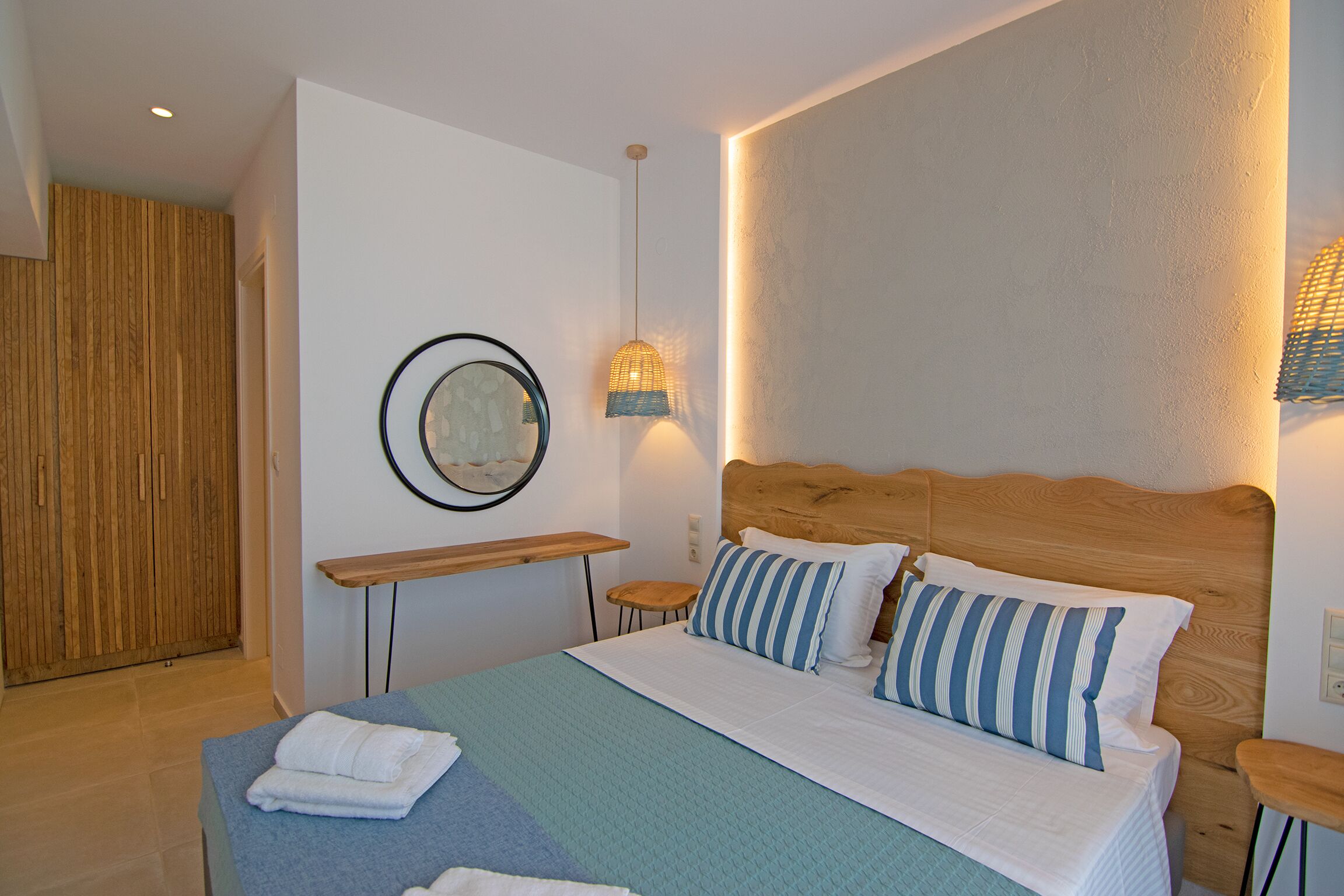 Un dormitorio con cama, mesitas de noche, un espejo y un cabecero de madera.
