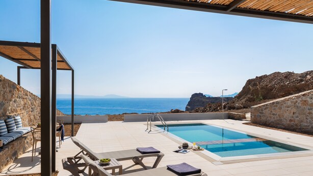 Un espace piscine avec des chaises longues et vue sur la mer.