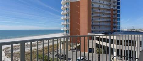A high-rise building with multiple balconies overlooking a beach.