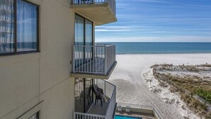 Un hôtel situé en bord de mer, doté de balcons avec vue sur l’océan, d’une piscine et d’une plage de sable.
