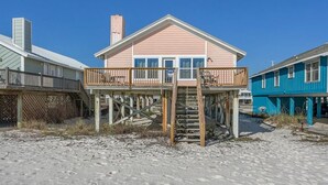 A beachfront house with a wooden deck and a staircase leading to the main entrance. - Kokomo by Meyer Vacation Rentals (Gulf Shores)