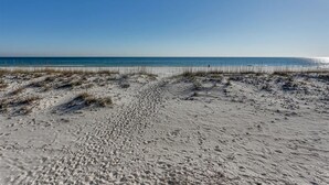 A sandy beach with a clear sky and calm sea. - Kokomo by Meyer Vacation Rentals (Gulf Shores)