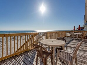 A wooden deck with a view of the beach and ocean.