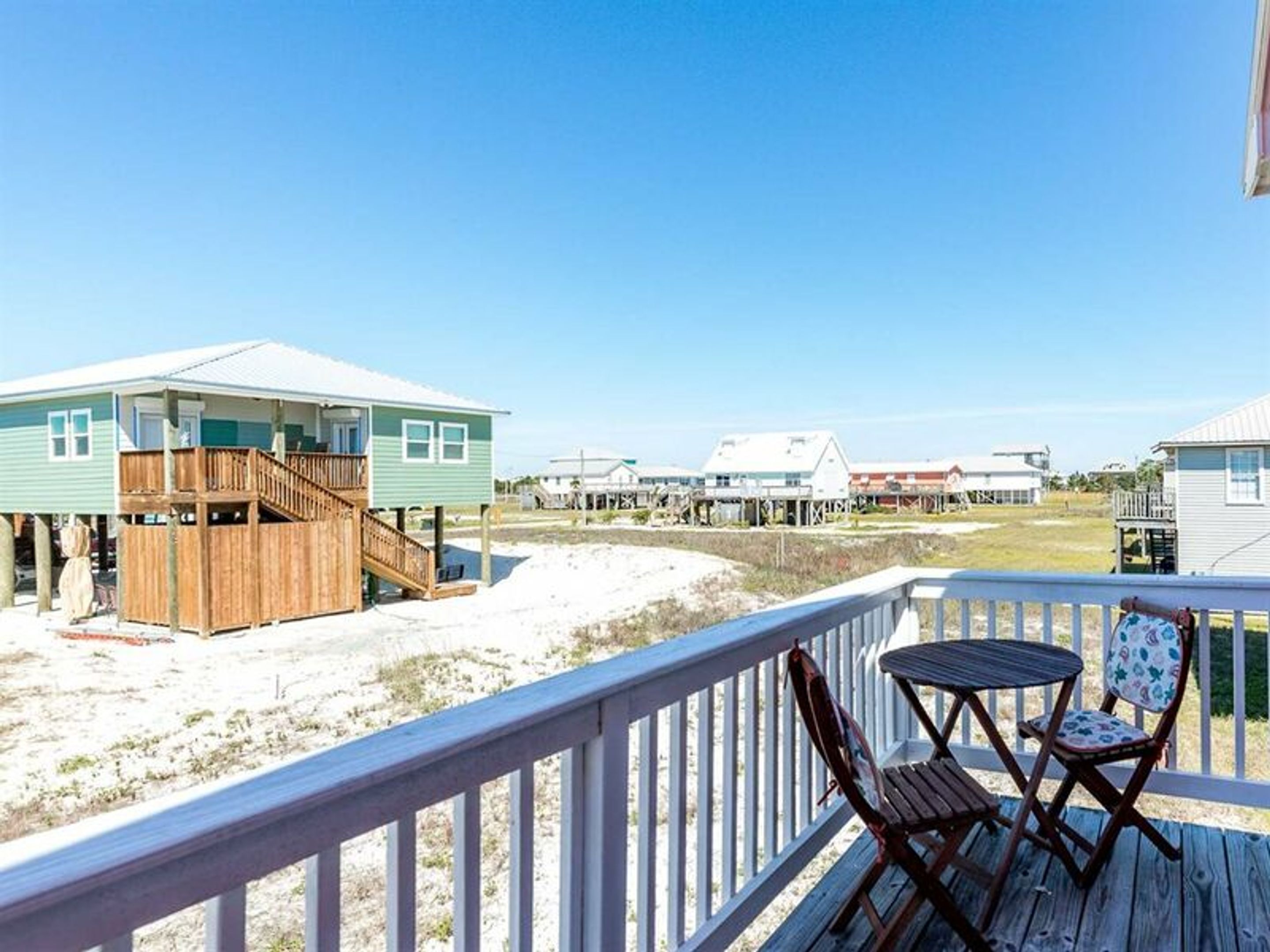 A beachfront property with a wooden deck and a small table and chair.