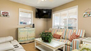 A living room with a sofa, a coffee table, a television, and a cabinet. - Red Robyn by Meyer Vacation Rentals (Gulf Shores)