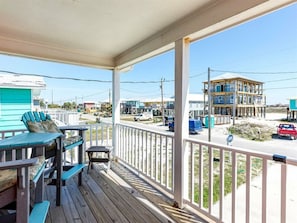 A wooden deck with outdoor furniture, a view of a beach, and a building under construction. - Red Robyn by Meyer Vacation Rentals (Gulf Shores)